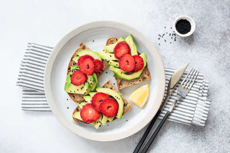 Healthy Vegan Toast With Avocado And Strawberries. Table Top View Concrete Backgroundの写真素材