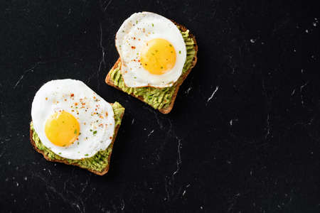 Fried egg and mashed avocado on toasted sandwich bread.の写真素材