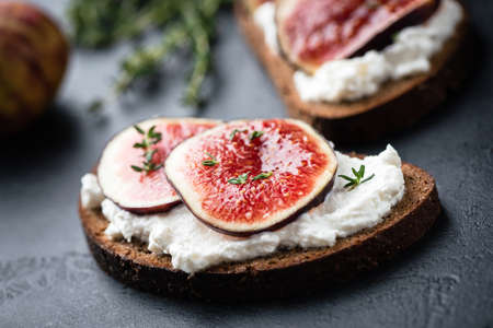 Rye bread toast with figs and ricotta cheese on black slateの写真素材