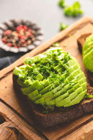 Avocado on rye bread toast garnished with chopped parsley, closeup view. Healthy snack, vegan or vegetarian breakfastの写真素材
