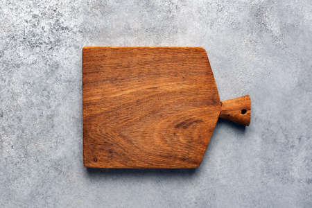 Rough square modern wooden cutting board on concrete background. Top view copy space. Kitchen,...