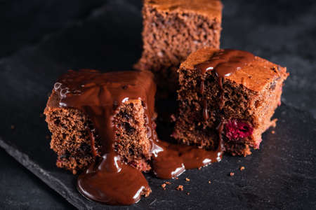 Chocolate brownie cake with chocolate sauce served on black slate.