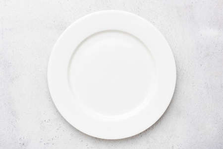 Empty white plate on grey cement concrete  with copy space, table top view.