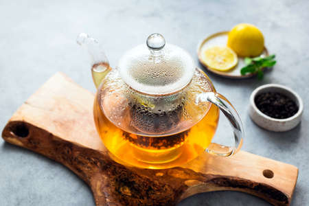 Tea in glass tea pot with lemon and mint. Fresh tea brew, herbal tea
