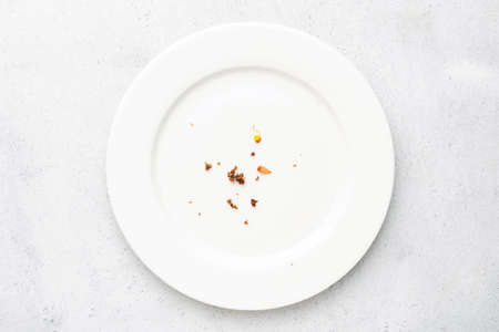 White plate with crumbs leftovers on grey concrete background. Top viewの写真素材