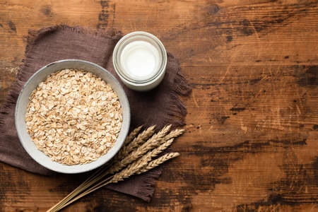 Rolled oats, oat flakes and oat milk on wooden table background, top view. Healthy diet food, clean eating and weight loss concept. Vegetarian vegan foodの写真素材