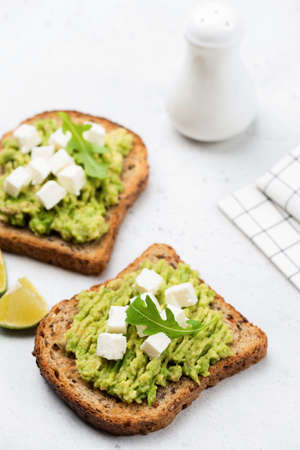 Avocado and feta cheese whole grain toast. Healthy vegetarian snack food or breakfast on white backgroundの写真素材