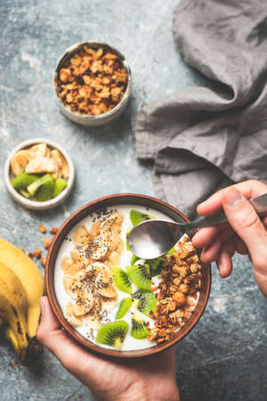 Healthy fruit granola bowl with yogurt. Clean eating, healthy lifestyle, vegetarian diet concept. Yogurt with banana, kiwi, chia seeds and crunchy honey granolaの写真素材