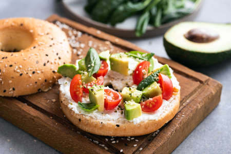 Bagel with cream cheese, avocado and tomatoes garnished with hemp seeds.の写真素材