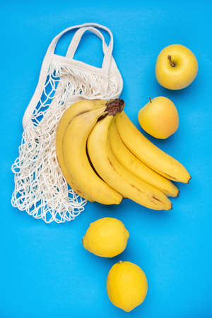 Zero Waste concept. Organic fruits and reusable mesh bag on a blue