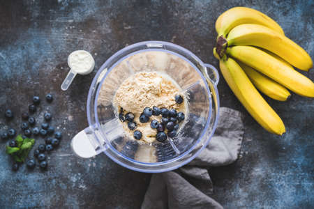 Blueberry protein powder in blender, smoothie preparation, top view. Concept of fitness healthy...