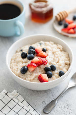 Oatmeal with strawberries and blueberries on grey concrete table
