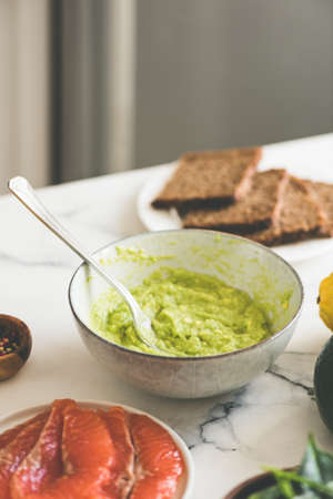 Avocado smash sauce in bowl on marble table, healthy eating food concept