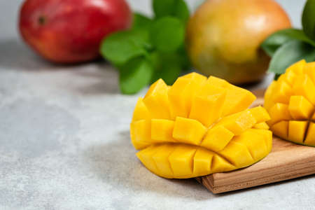 Mango halved on wooden cutting board with copy space for text. Fresh ripe tropical fruit mangoの写真素材