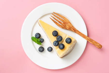 Cheesecake slice with blueberries on pink background, table top viewの写真素材