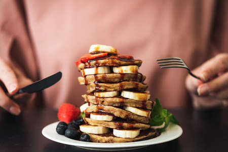Pancakes with banana chocolate sauce and strawberries. Stack of delicious pancakes. Sugar bomb, carbohydrates food, sweet breakfast pancakesの写真素材