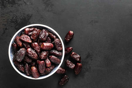 Dried dates in bowl on black