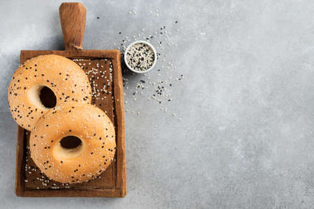 Two sesame bagels on grey concrete background, top view copy space for text or design. Freshly baked...