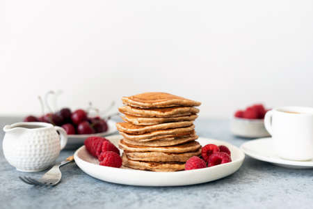 Healthy oat Pancakes with berries and syrup on table, white background, copy space for text....