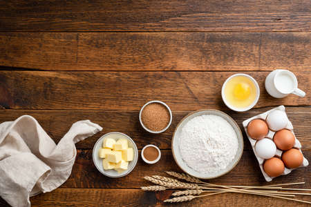 Ingredients for baking on a rustic wooden background. Flour, eggs, butter, sugar and other ingredients for baking a cake, sweet bread pastry or cookiesの写真素材