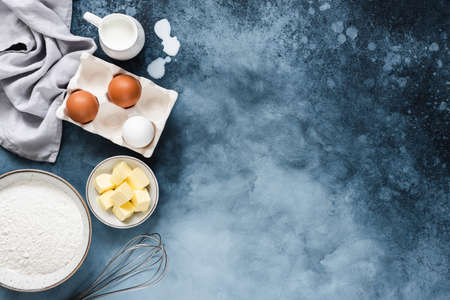 Ingredients for baking on a blue navy background with copy space. Flour sugar butter and milk for...