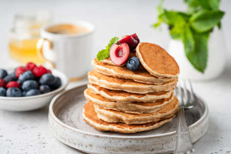 Healthy oat pancakes with berries on a craft ceramic plate. Vegan breakfast foodの写真素材