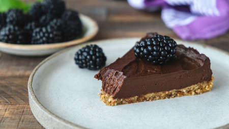 Vegan chocolate tart with blackberries. Slice of chocolate pie with bite missing