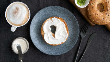 Toasted bagel with cream cheese and cup of coffee for breakfast, top viewの写真素材