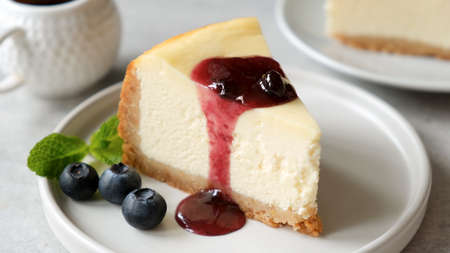 Slice of cheesecake with blueberry sauce on white plate. Delicious cakeの写真素材