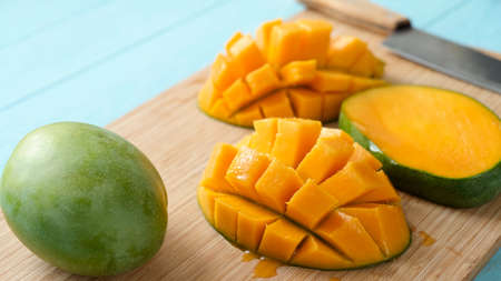 Delicious ripe mango cut in chunks on a wooden cutting board. Tropical fruit juicy mangoの写真素材