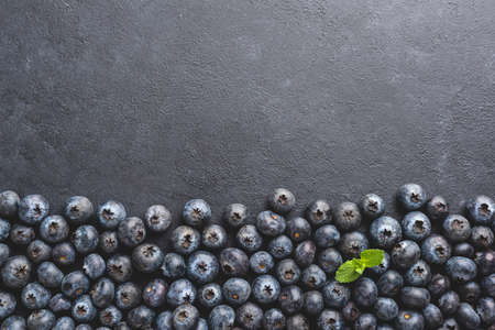 Blueberries as background over black concrete backdrop with copy space for text or design. Top viewの写真素材