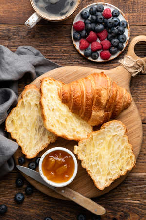 French croissants with berries and jam on a wooden background, top view. Halved croissants, croissant textureの写真素材