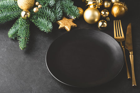 Elegant Christmas, New Year table setting in black. Black plate, golden color silverware, fir tree and toys. Copy space for text, designの写真素材