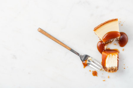 Broked slice of cheesecake with caramel sauce. Eating cheesecake processの写真素材