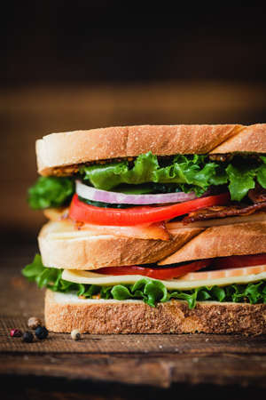 Tall club sandwich with bacon, turkey, cheese, lettuce and tomatoes. Closeup viewの写真素材