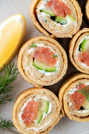 Crepe rolls with salmon, cucumber and cream cheese on a plate, top viewの写真素材