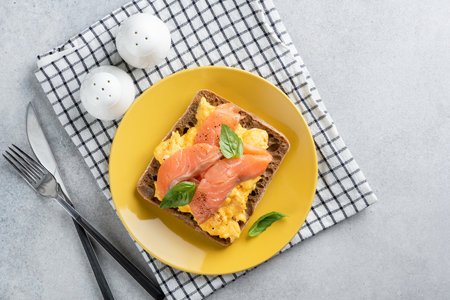 Scrambled egg and smoked salmon toast on a yellow plate, closeup viewの写真素材