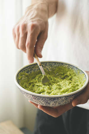Male chef mashing avocado with fork in a bowl. Making guacamole sauceの写真素材