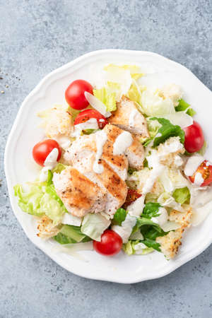 Caesar salad with grilled chicken breast, cherry tomatoes and lettuce salad topped with traditional caesar salad dressing. Top viewの写真素材