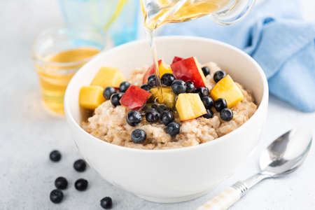 Cooked oatmeal with peach and blueberries in a bowl, closeup viewの写真素材