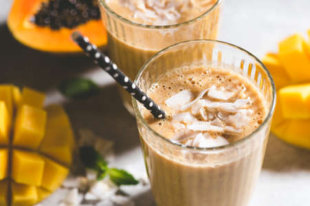 Vegan mango coconut smoothie cocktail with paper drinking straw. Closeup viewの写真素材