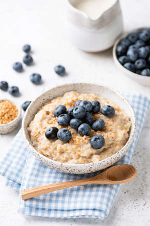 Oatmeal bowl with blueberries and flax seeds on blue textile. Healthy breakfast mealの写真素材