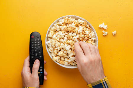 Popcorn in bowl and TV remote controlの写真素材