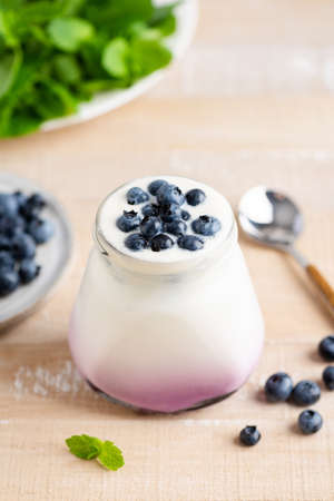 Blueberry yogurt in a jar on wooden table background. Healthy food rich in protein and calcium, weight loss productの写真素材