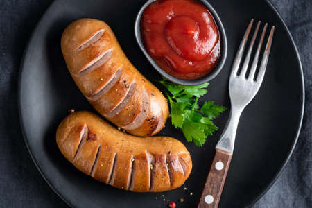 Grilled sausages and ketchup on plateの写真素材