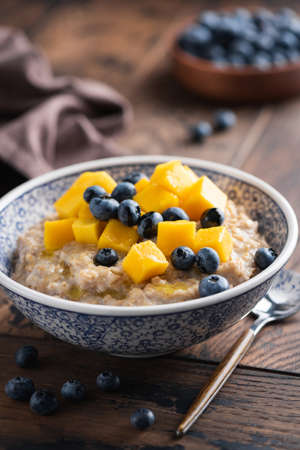 Oatmeal bowl with mango and blueberriesの写真素材