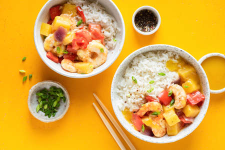 White rice with shrimps and pineapple in bowl on yellow background, top viewの写真素材
