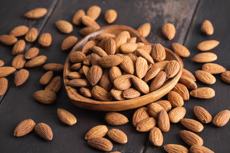 Raw almonds in a heart shaped wooden bowl on old table, Healthy vegan snack foodの写真素材
