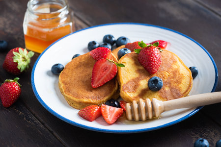 Delicious pancakes with berries and honey on plate, closeup viewの写真素材