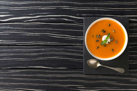 pumpkin soup with pumpkin seed and mint leaf in black wooden background. top view and copy space.の写真素材